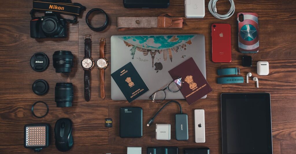 Flat lay of travel essentials including gadgets, passports, and camera on wooden surface.